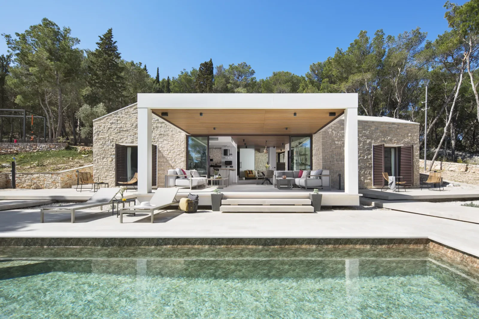 Contemporary private coastal estate beside a stone-lined pool among pine trees